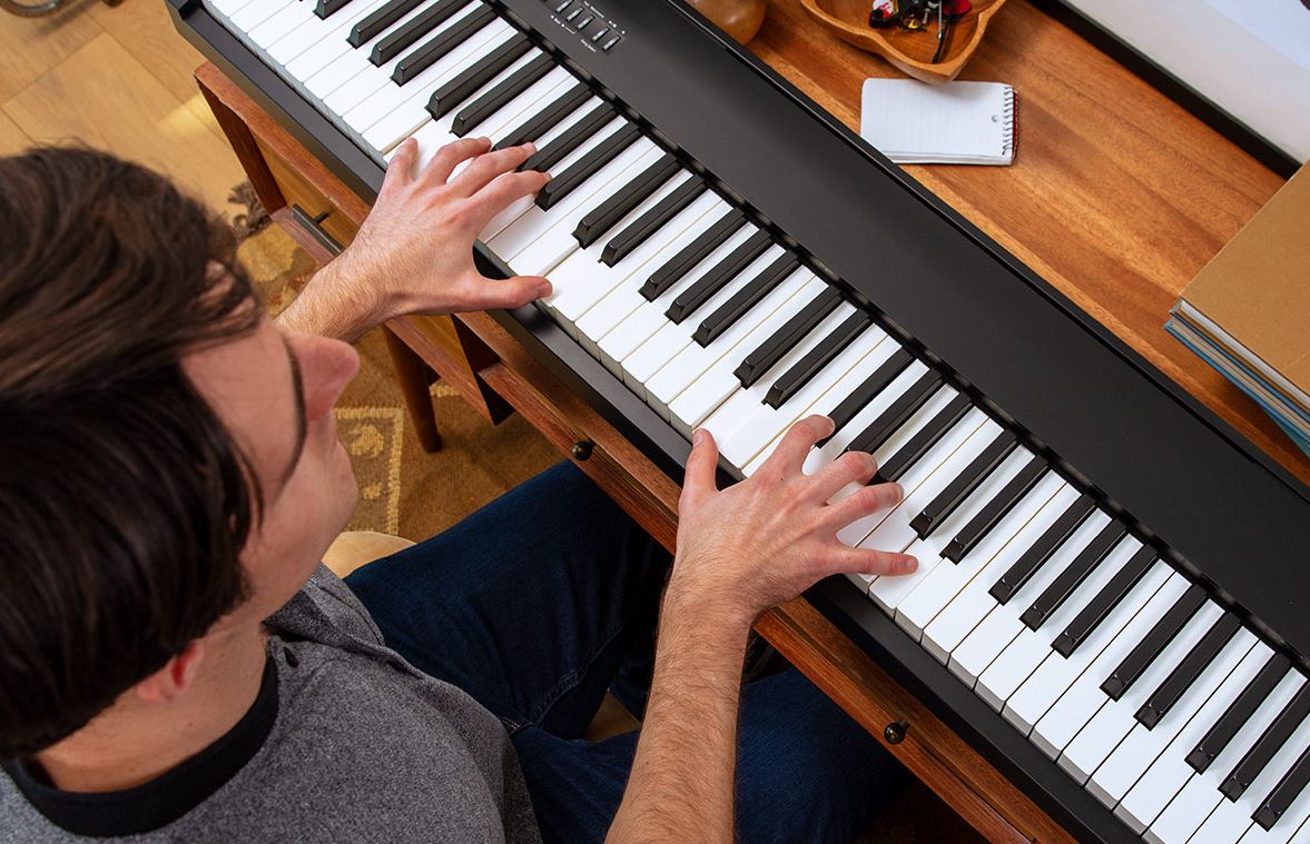 un homme joue du piano électronique posé sur son bureau