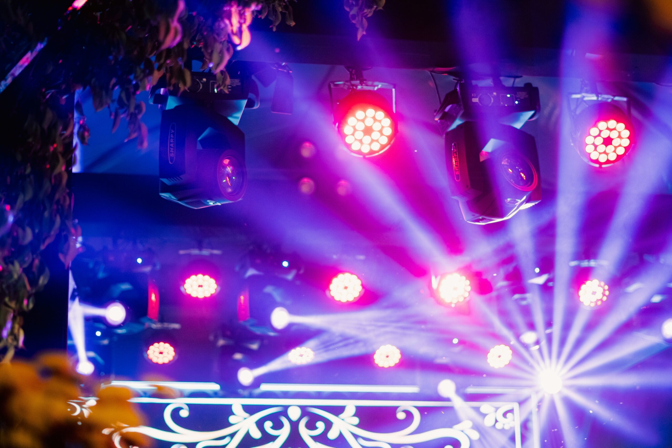 Scène événementielle avec faisceaux colorés issus de lyres beam, projecteurs PAR LED au sol et effets laser, ambiance club/soirée
