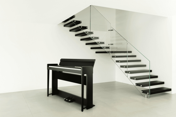 Piano numérique meuble Korg C1 Air noir installé dans un intérieur moderne, avec pédalier et clavier 88 touches