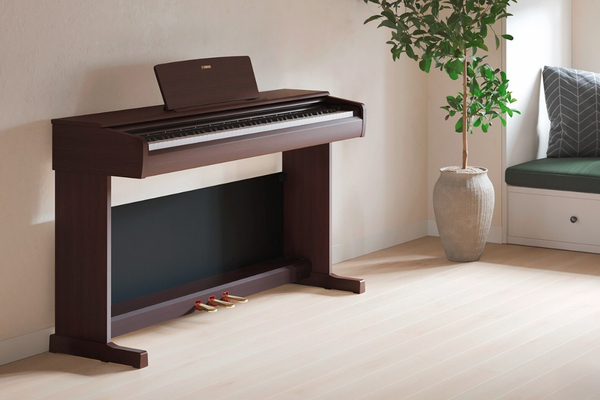 Piano numérique meuble Yamaha YDP-S144 R Arius bois de rose avec pupitre et pédalier, installé dans un intérieur chaleureux