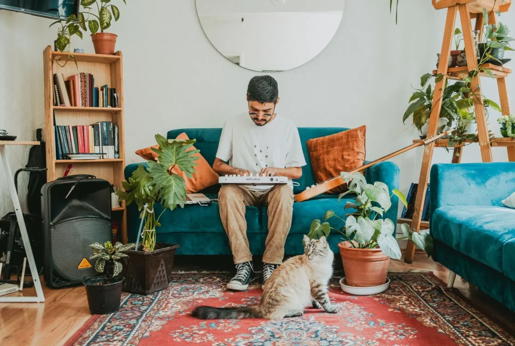Musicien jouant sur un contrôleur Arturia MiniLab posé sur les genoux depuis un canapé, illustrant la portabilité et l'utilisation nomade du format compact