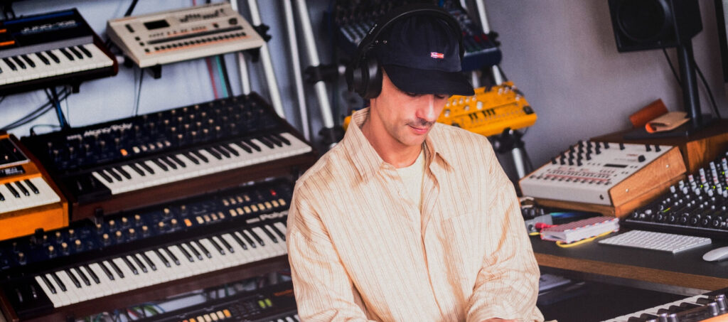 Producteur portant un casque AIAIAI dans un studio équipé de synthétiseurs