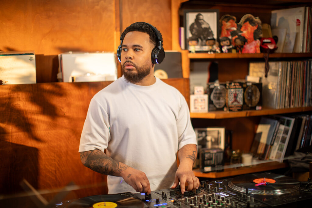 DJ portant le casque sans fil faible latence AlphaTheta HDJ-F9 devant des platines vinyles