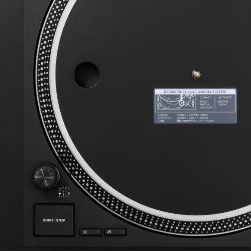 Gros plan sur le plateau de la Technics SL-1210MKX avec étiquette DIP switch, bouton start/stop et sélecteur de pitch